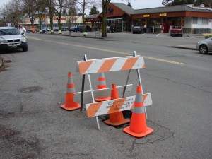 The QFC grocery store (background) is in Wedgwood's busy commercial district where the streets take a beating from the heavy traffic, as seen by this pothole.