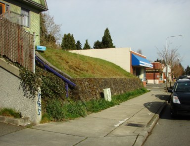 The Big Green House at 7321 35th Ave NE has a retaining wall which shows that the house was there long before road-grading.